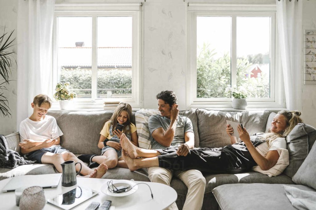 Happy family sitting on sofa in living room - Financing for roof